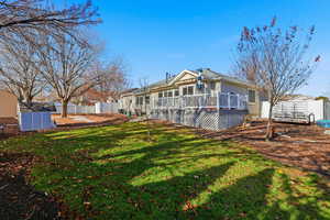 Rear view of house featuring a fenced backyard, a deck, and a shed