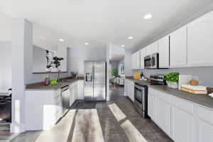 Kitchen with stainless steel appliances, white cabinetry, dark countertops, and recessed lighting