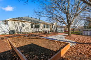 Back of house featuring a shingled roof and a vegetable garden