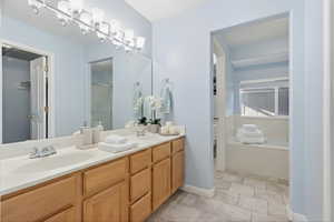 Bathroom featuring double vanity, a bath, and light stone finish flooring