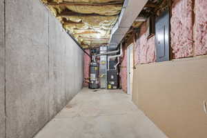 Unfinished basement with electric panel, water heater, and heating unit