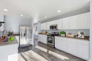 Kitchen with stainless steel appliances, white cabinets, and recessed lighting