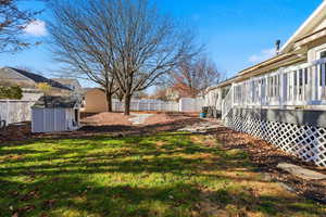Fenced backyard featuring a storage unit and a wooden deck