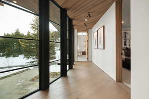 Hall with floor to ceiling windows, light wood-style flooring, wood ceiling, and recessed lighting