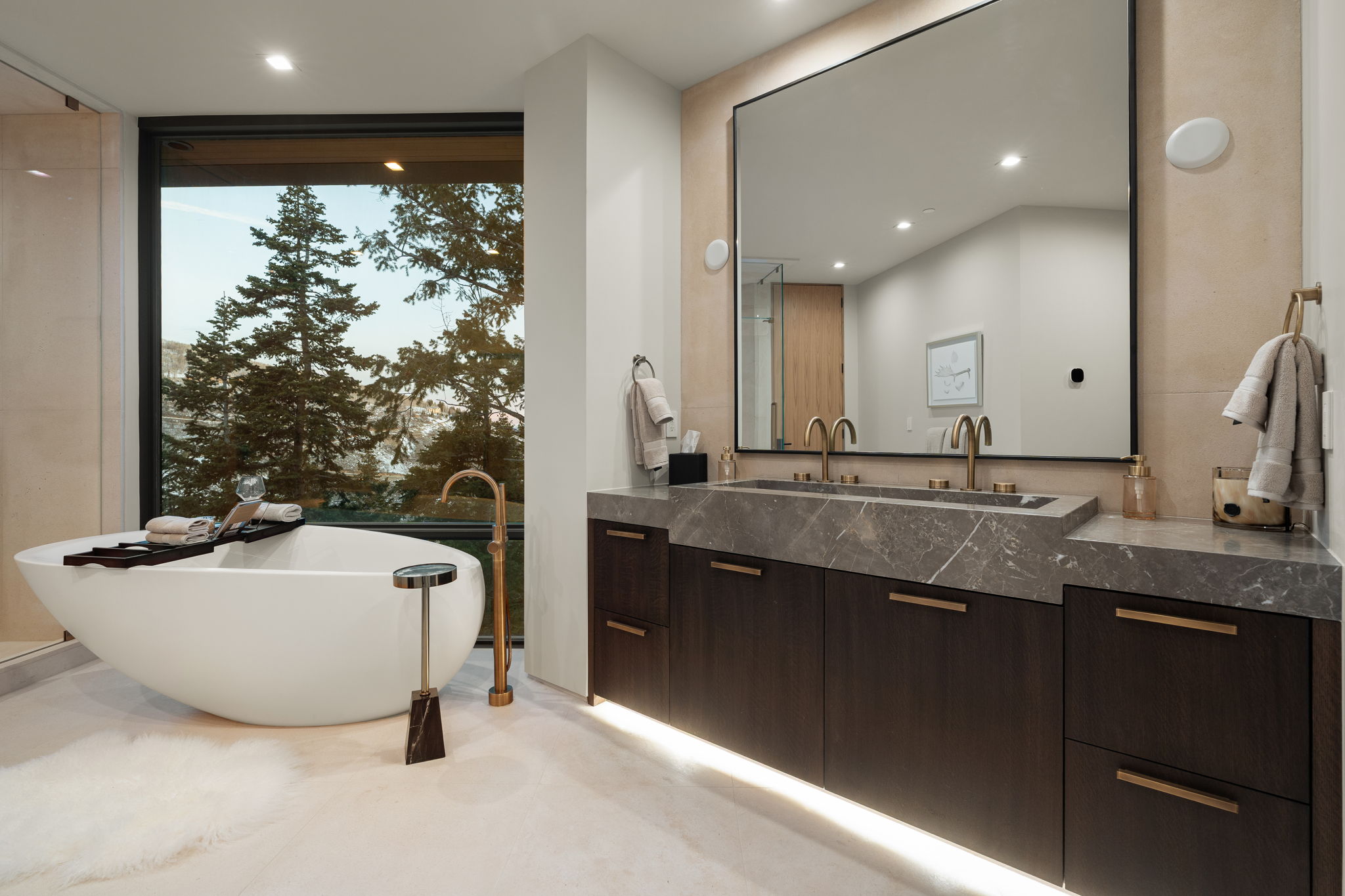 Bathroom with a freestanding tub, double vanity, floor to ceiling windows, and recessed lighting