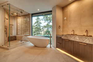 Bathroom featuring floor to ceiling windows, a freestanding bath, a shower stall, vanity, and recessed lighting