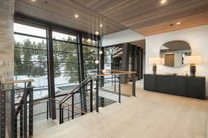 Hall featuring expansive windows, wooden ceiling, an upstairs landing, light wood-style flooring, and recessed lighting
