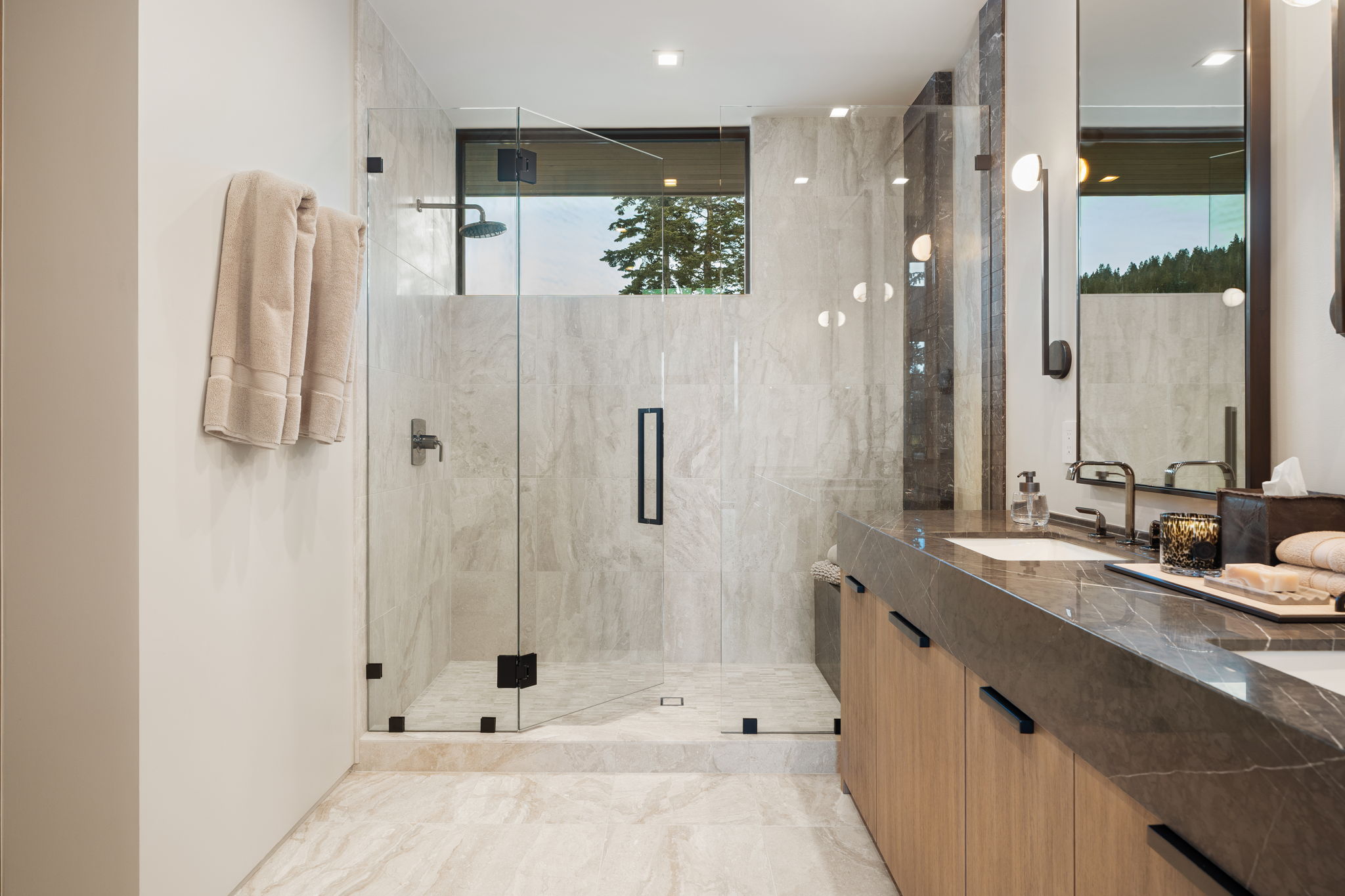 Bathroom with double vanity, a marble finish shower, and plenty of natural light