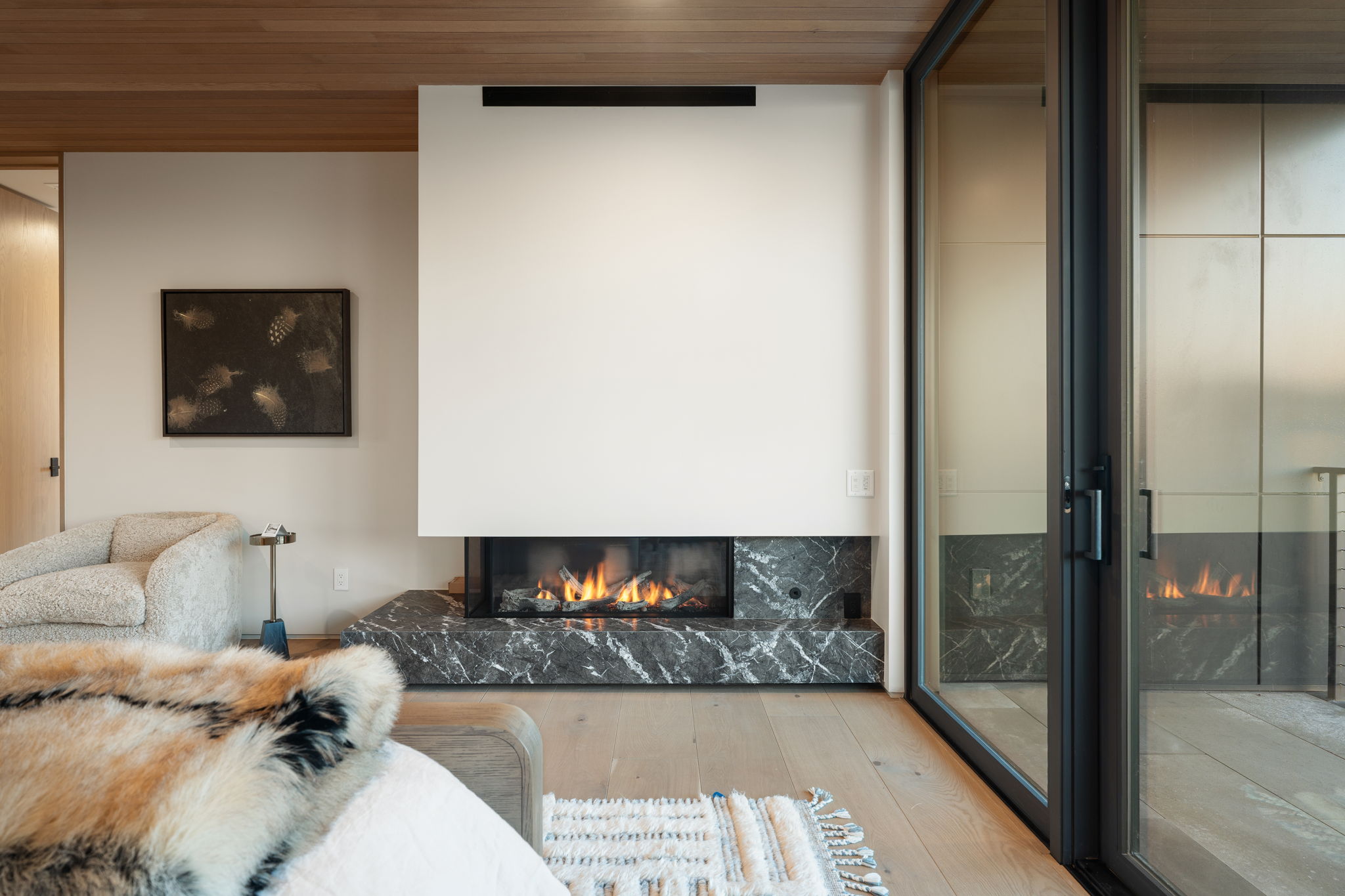 Living area featuring a high end fireplace, light wood finished floors, and wooden ceiling