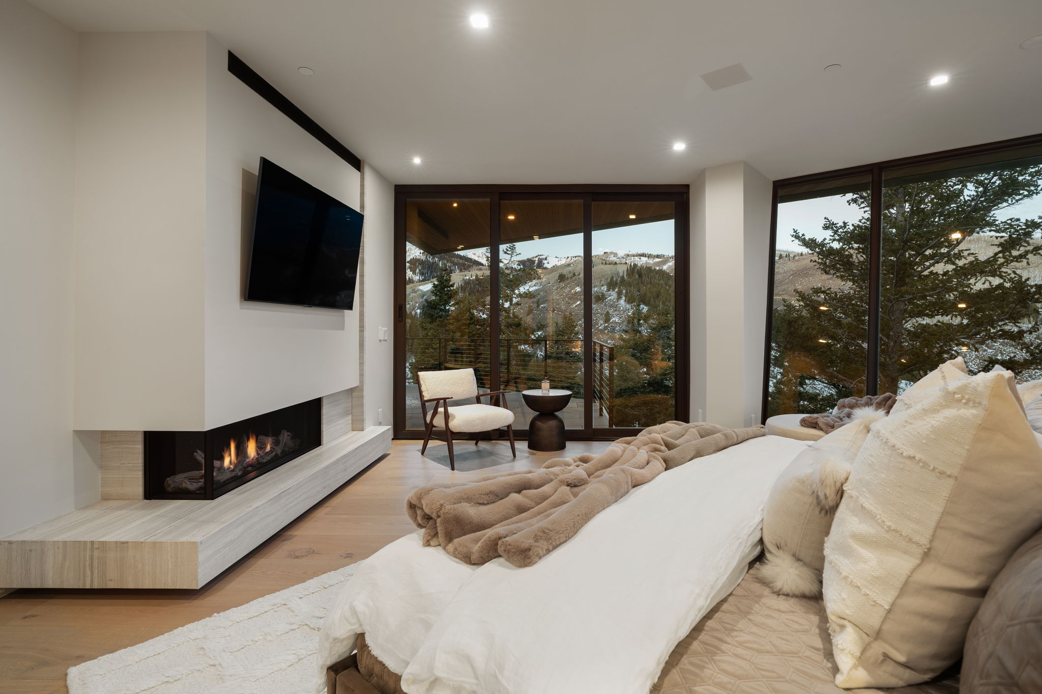 Living area with expansive windows, wood finished floors, recessed lighting, and a lit fireplace