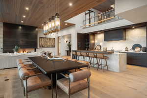 Dining space featuring light wood-style flooring, a high wood ceiling, recessed lighting, a fireplace, and wet bar