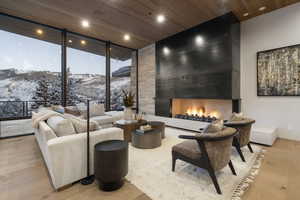 Living area featuring a large fireplace, light wood-style floors, a wall of windows, a mountain view, and recessed lighting