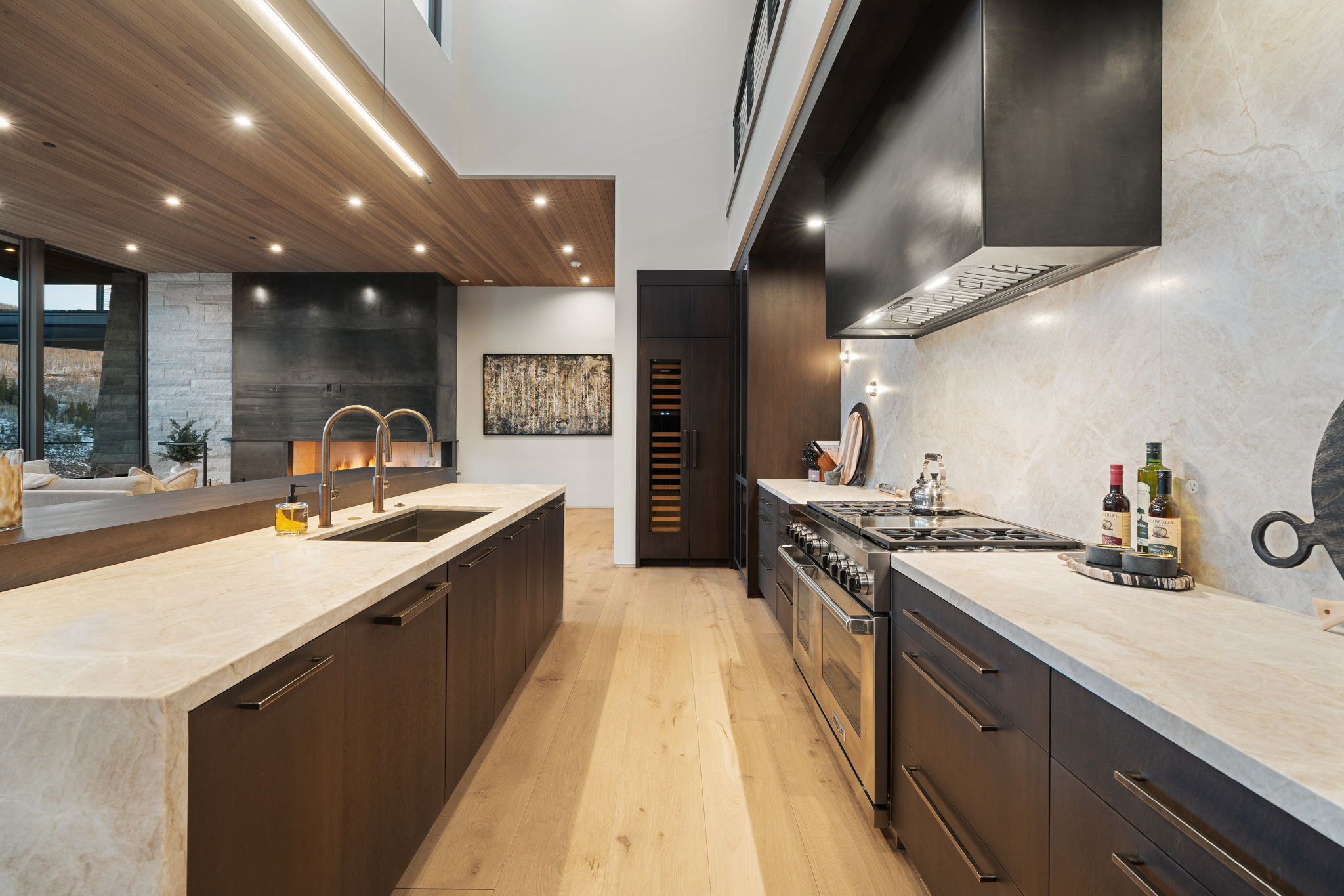 Kitchen with dark wood finish cabinets, range with two ovens, light stone countertops, light wood finished floors, and recessed lighting