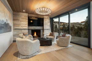 Living area featuring wooden ceiling, hardwood / wood-style floors, a stone fireplace, recessed lighting, and expansive windows