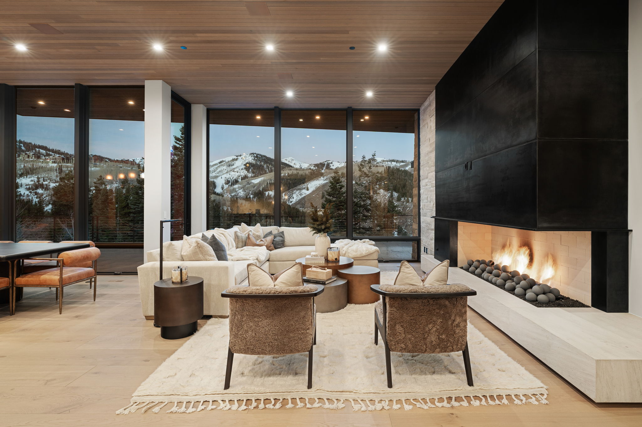 Living room with a mountain view, wooden ceiling, light wood-type flooring, a large fireplace, and floor to ceiling windows