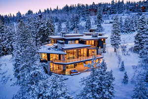 Snow covered property with stone siding and a balcony