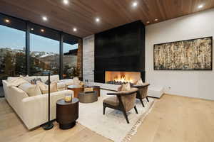 Living room with wood ceiling, light wood-type flooring, a large fireplace, recessed lighting, and a mountain view