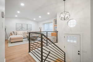 Living room with lofted ceiling, light wood-style flooring, recessed lighting, and a chandelier