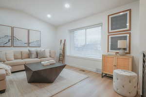 Living area with lofted ceiling, light wood-style flooring, and recessed lighting