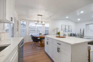 Kitchen with white cabinets, pendant lighting, a kitchen island, recessed lighting, and light wood-style flooring