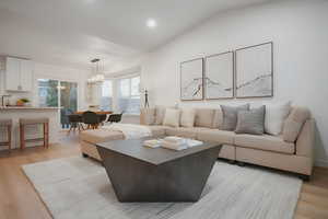 Living area with light wood finished floors, lofted ceiling, and recessed lighting