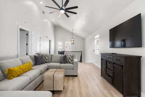 Living room featuring high vaulted ceiling, light wood-style floors, and ceiling fan