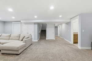 Living area featuring light carpet, stairway, and recessed lighting