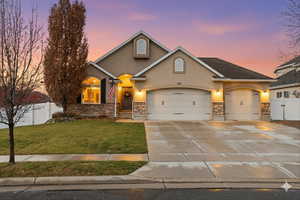 View of front of house featuring stucco siding, stone siding, driveway, and a garage