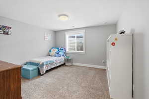Bedroom featuring light carpet and baseboards