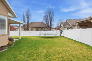 Fenced backyard featuring a trampoline, a residential view, and a patio