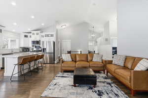 Living room with a chandelier, dark wood-style flooring, high vaulted ceiling, and recessed lighting