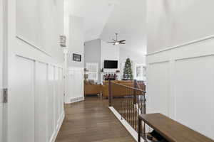 Hallway featuring an upstairs landing, dark wood-style flooring, a decorative wall, and high vaulted ceiling