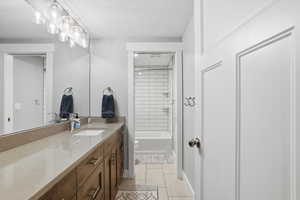 Bathroom with vanity, washtub / shower combination, and light tile patterned flooring