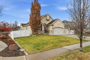 View of front of home featuring stucco siding, stone siding, concrete driveway, a gate, and a garage