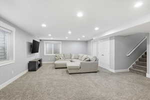 Living room with recessed lighting, stairway, and light carpet