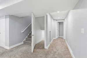 Hallway with light colored carpet, stairway, and recessed lighting