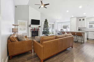 Living area featuring ceiling fan, healthy amount of natural light, dark wood-style flooring, and high vaulted ceiling