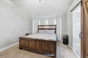 Bedroom with a barn door and light colored carpet