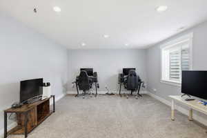 Office space with light colored carpet and recessed lighting