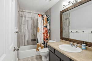 Bathroom with shower / tub combo with curtain, vanity, and a textured ceiling