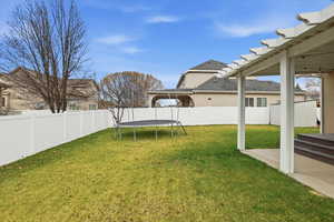 Fenced backyard with a trampoline and a patio area
