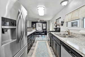 Kitchen with newer appliances with stainless steel finishes, dark cabinetry, light countertops, a textured ceiling, and light wood finished floors