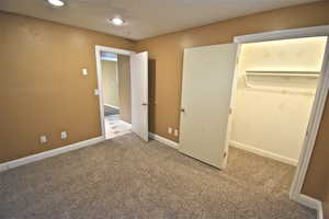 Unfurnished bedroom featuring carpet floors, a spacious closet, and recessed lighting