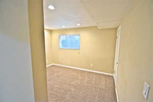 Carpeted spare room featuring recessed lighting and attic access