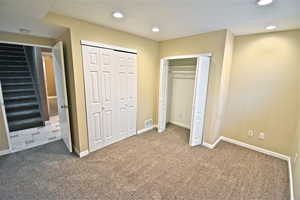 Unfurnished bedroom with carpet, recessed lighting, and two closets