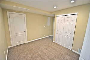 Unfurnished bedroom with carpet, a closet, attic access, recessed lighting, and electric panel
