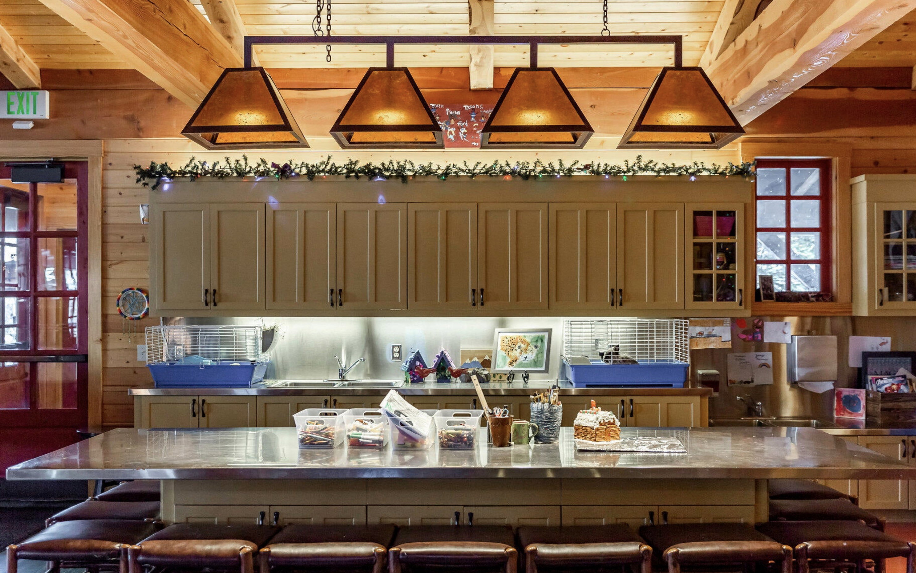 Kitchen featuring decorative light fixtures, a breakfast bar area, wooden walls, a spacious island, and glass insert cabinets