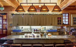 Kitchen featuring decorative light fixtures, a breakfast bar area, wooden walls, a spacious island, and glass insert cabinets