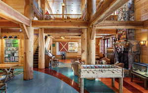 Recreation room with wooden walls, a towering ceiling, and a stone fireplace