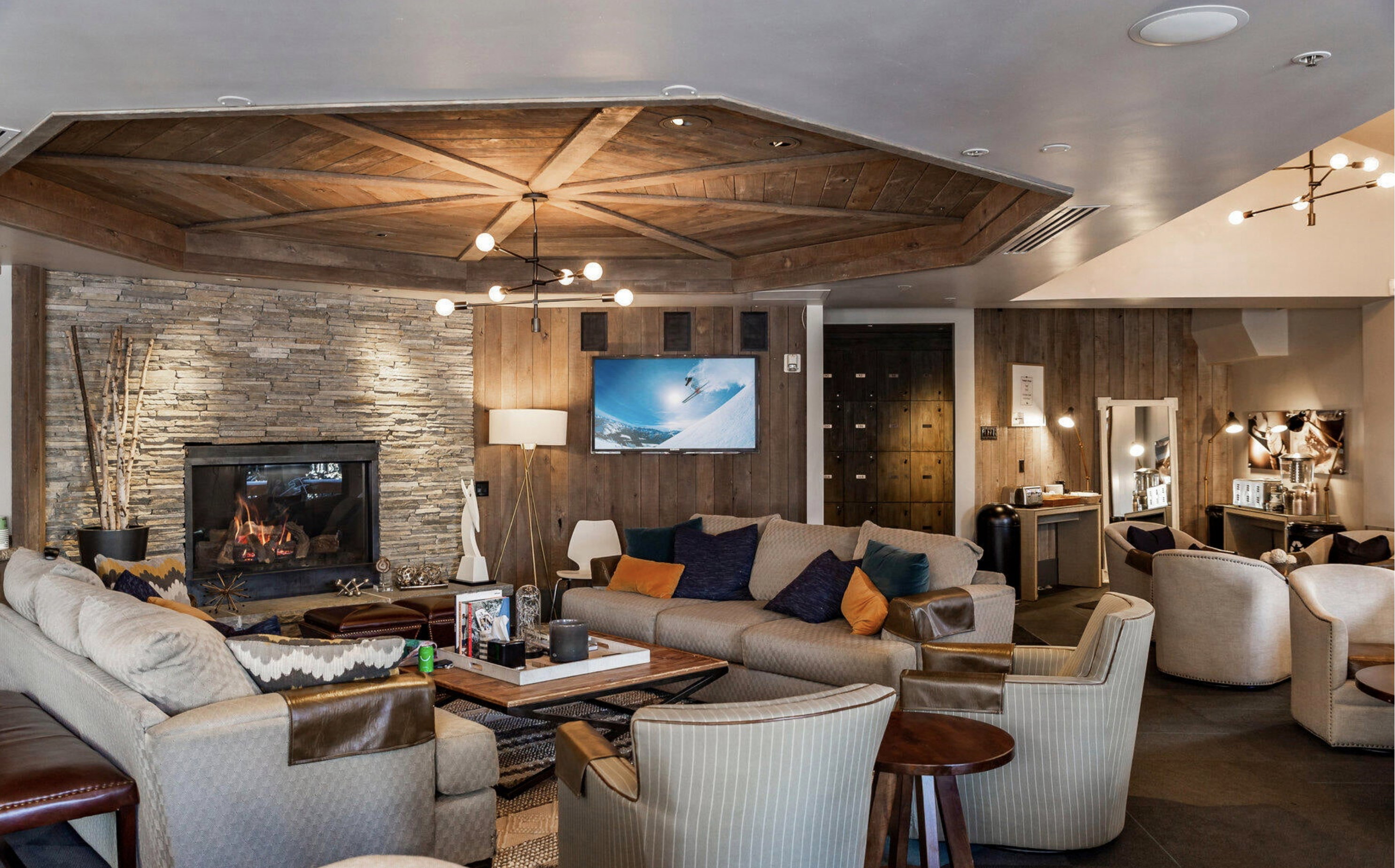 Living room featuring wood ceiling, a fireplace, a chandelier, wood walls, and a raised ceiling
